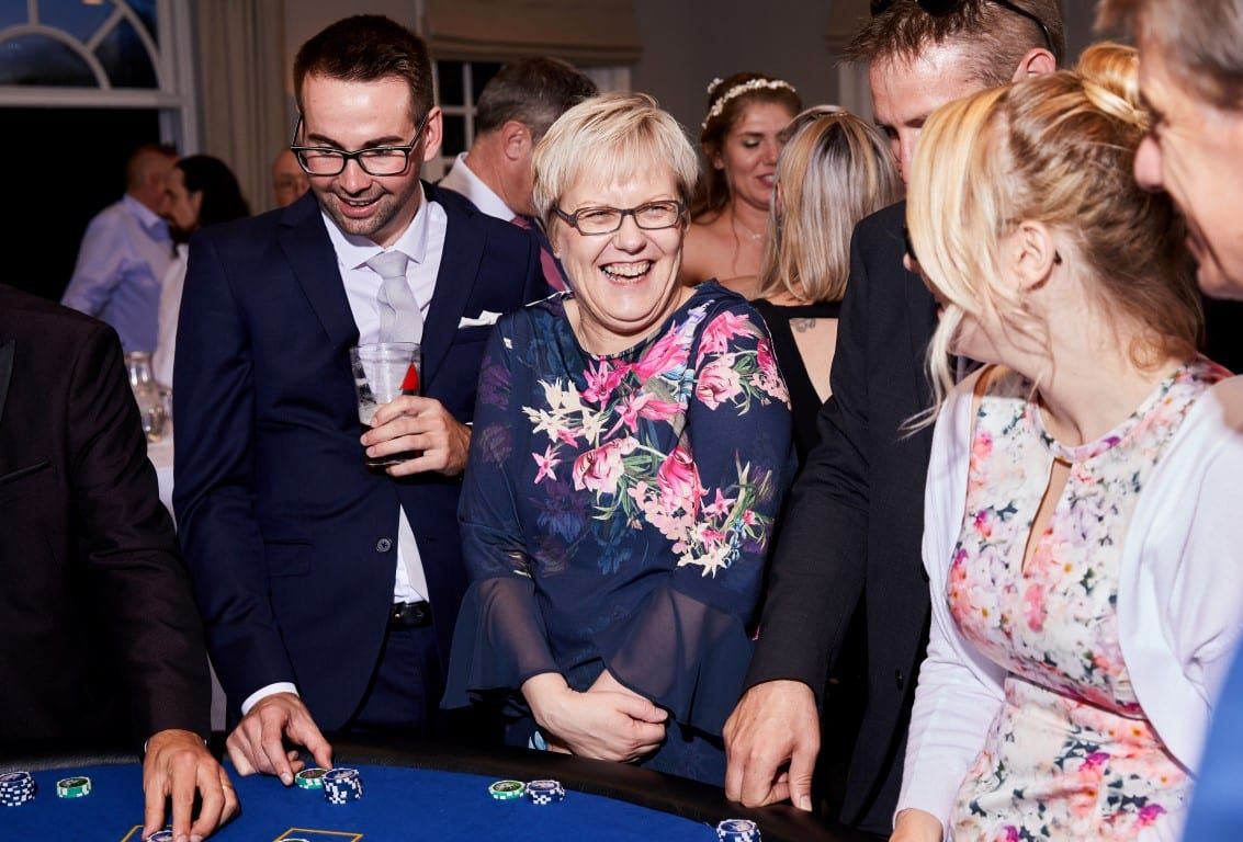 Guests laughing around a blackjack table at an evening event