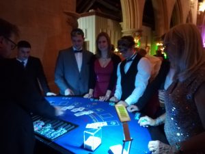 Guests in black tie playing blackjack at a lit-up table