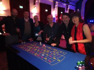 Group of guests smiling around a roulette table