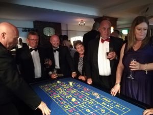 Guests in black tie gathered at a roulette table