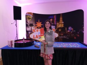 Guest posing with a Las Vegas sign prop beside a roulette table