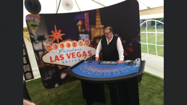 Croupier at a blackjack table in front of a Las Vegas backdrop