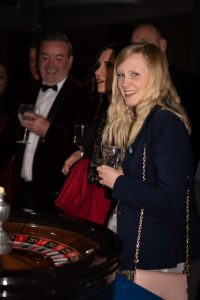 Guest smiling at a roulette table at a black tie event