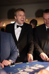 Guests in black tie laughing at a casino table