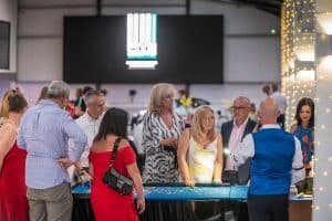 Crowd of guests around a casino table at a summer ball