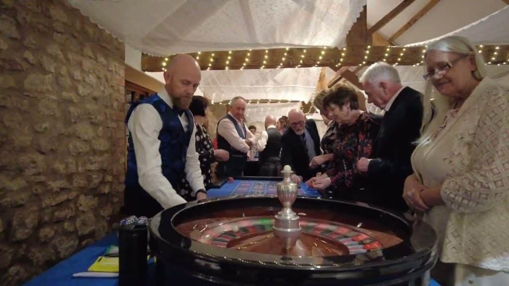 Croupier running a roulette table for wedding guests in a barn