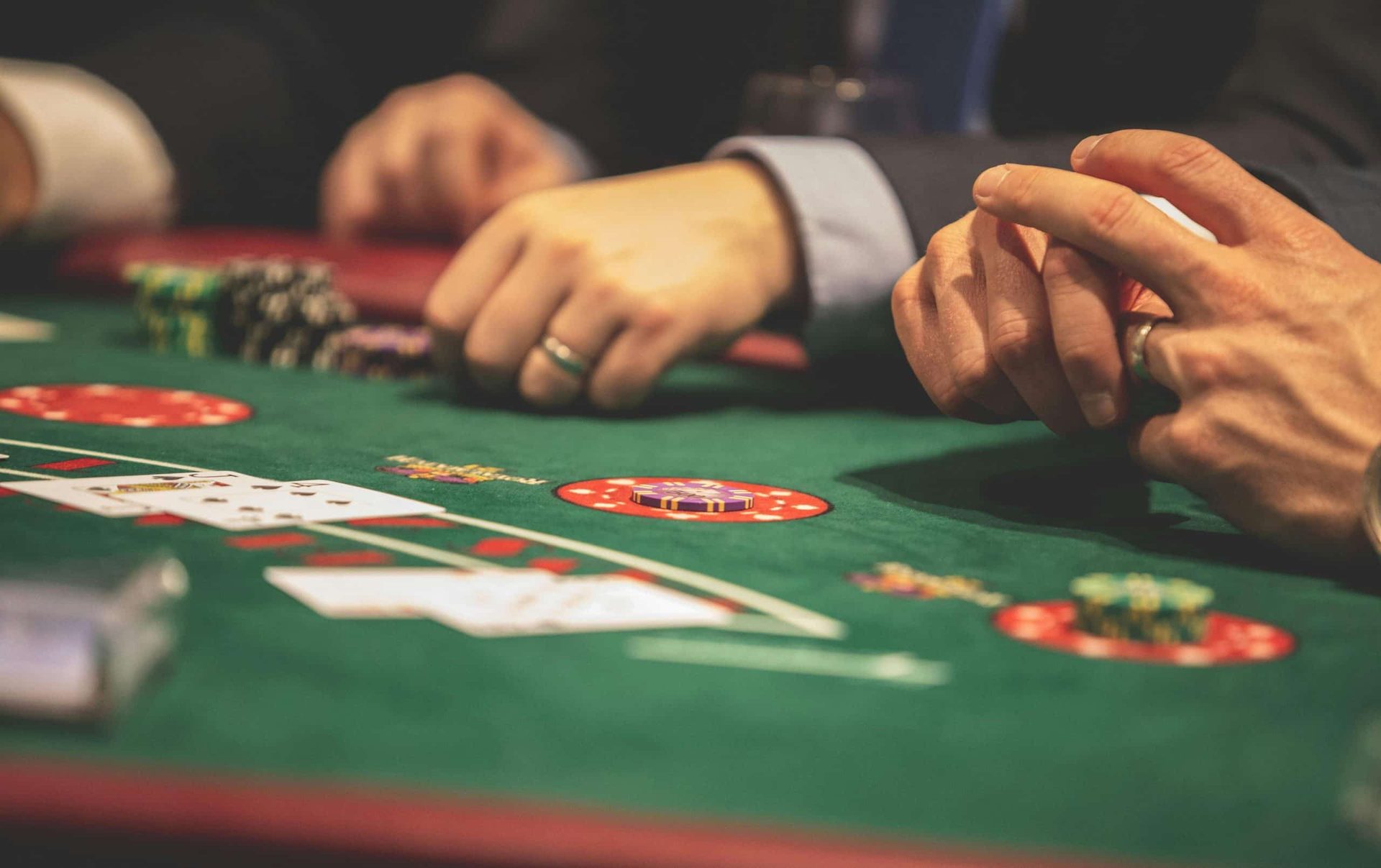 Players' hands with chips at a green poker table