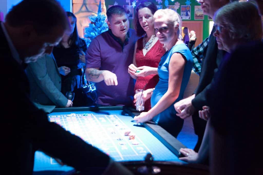 Guests playing at a casino table under blue party lighting