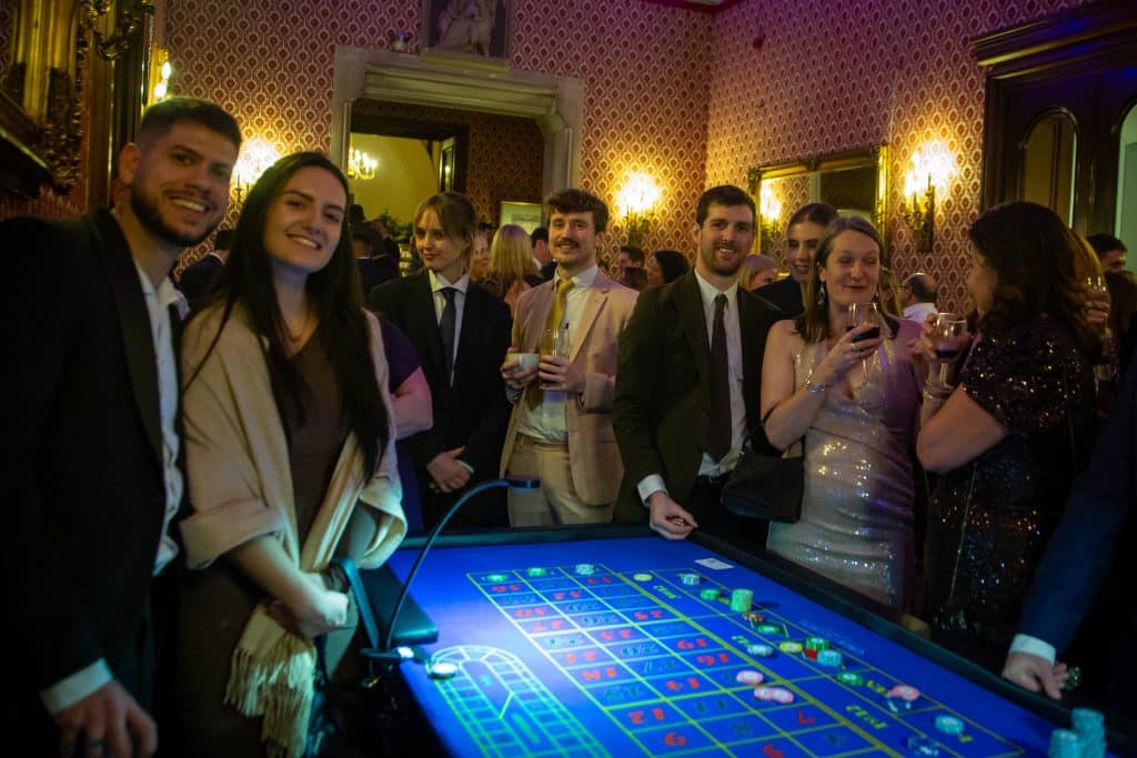 Guests smiling at a roulette table in a grand venue