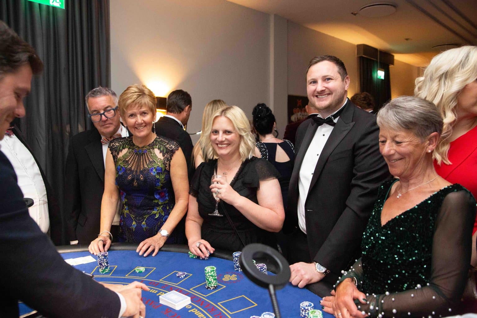 Guests in evening wear laughing at a blackjack table