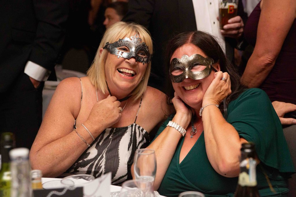 Two guests in masquerade masks laughing