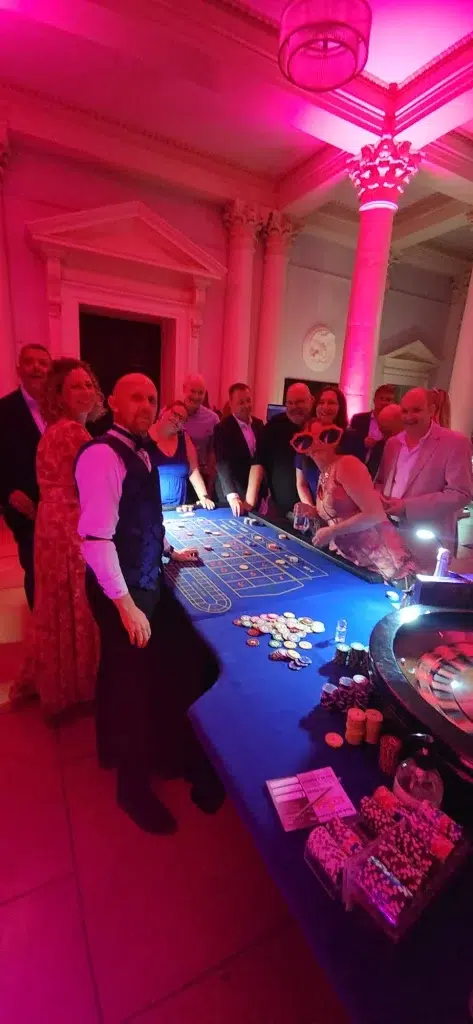 Guests and a croupier around a roulette table at a school prom at Prior Park in Bath