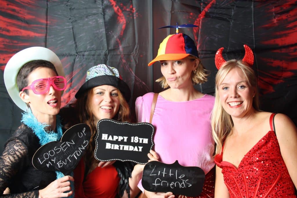 Party guests wearing colourful wigs and glasses in the open-air photo booth