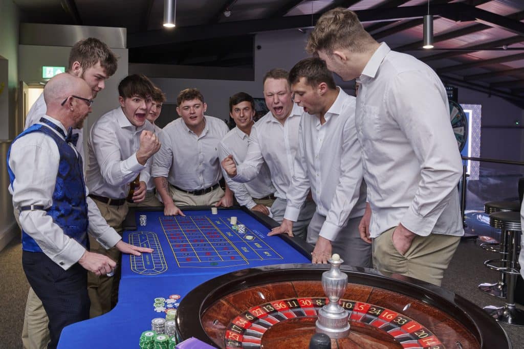 Group of young men cheering at a roulette table