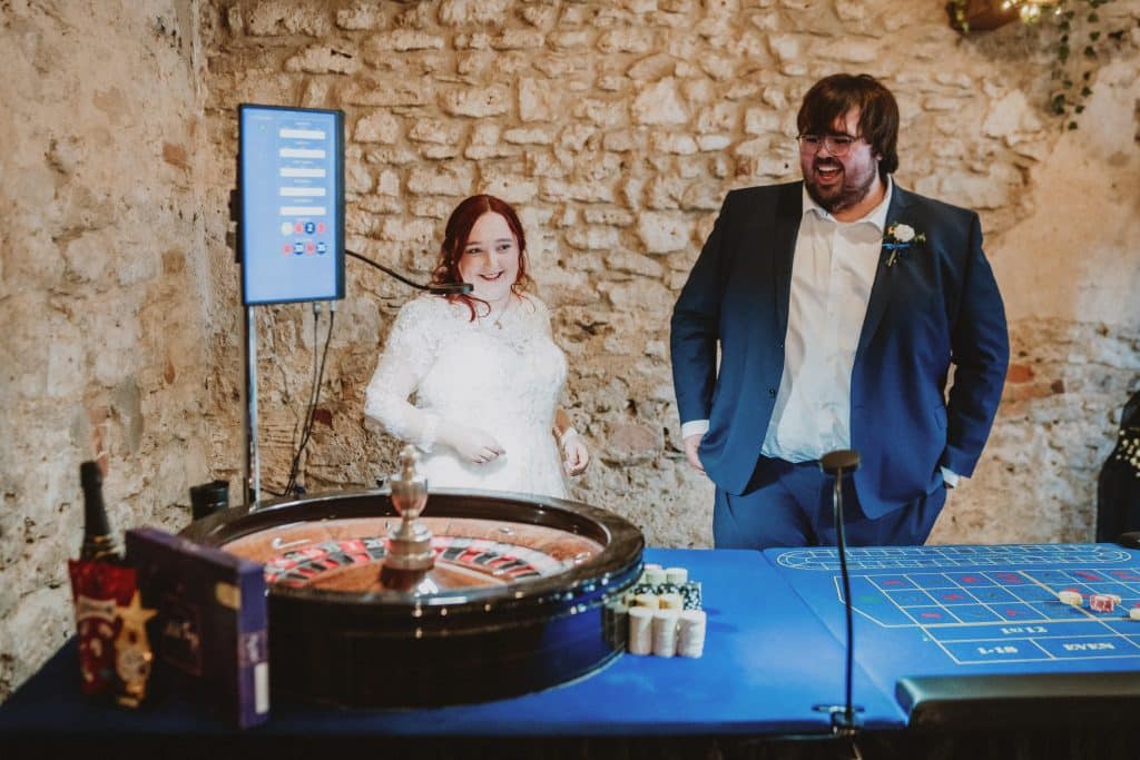 Bride and groom at a Fun Casino Fun roulette table in a barn venue